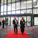 Two people walking down a red carpet and smiling