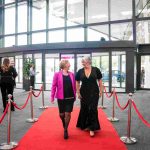 Two people walking down a red carpet and smiling