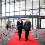 Two people walking down a red carpet and smiling