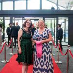 Two people standing on a red carpet and smiling