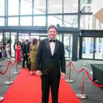 One person standing on a red carpet and smiling