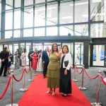 Two people standing on a red carpet and smiling