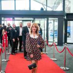 One person standing on a red carpet and smiling