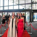 Two people standing on a red carpet and smiling