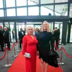 Two people standing on a red carpet and smiling