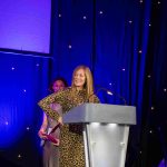 TV presenter and designer Anna Ryder Richardson standing behind a lectern on a presentation stage