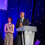 Olympic athlete and broadcaster Colin Jackson standing behind a lectern on a presentation stage