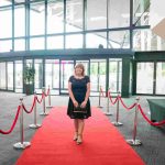 One person standing on a red carpet and smiling