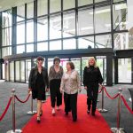 Four people walking down a red carpet and smiling