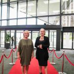 Two people standing on a red carpet and smiling