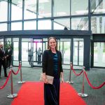 A person standing on a red carpet and smiling